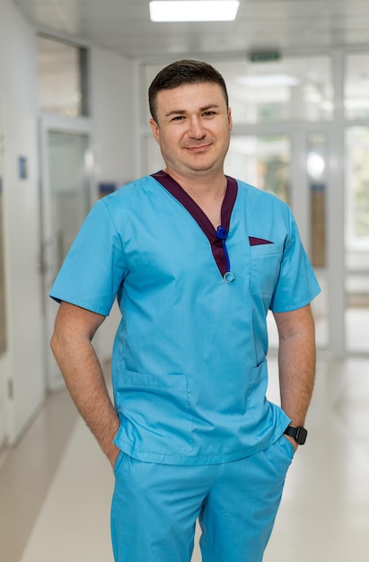 Membro da equipe médica em roupão de pé em um corredor do hospital Um profissional de saúde vestindo roupão azul está confiantemente em um hospital