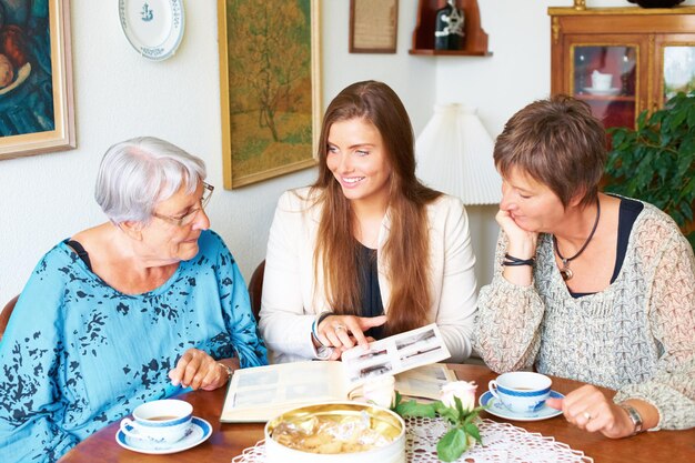 Foto memória de foto de família e almoço com mãe e avó com um sorriso juntos chá mulher idosa e casa mesa de jantar com mulheres e feliz do álbum para lembrar na aposentadoria em uma casa