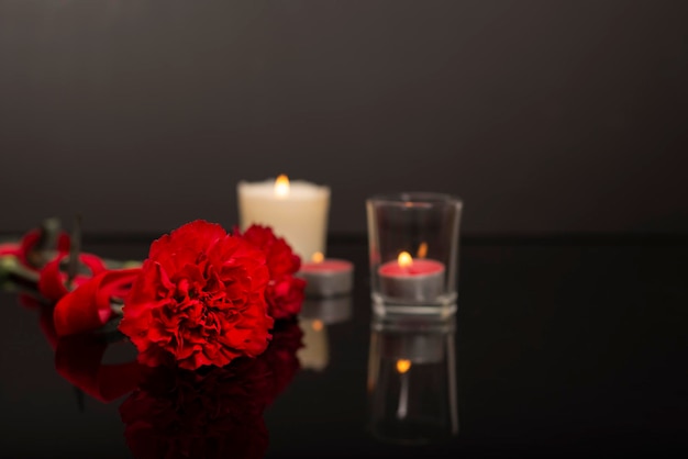 Foto memorial schwarz mit spiegeleffekt plakette mit blumen und kerzen, rote nelke und blumen