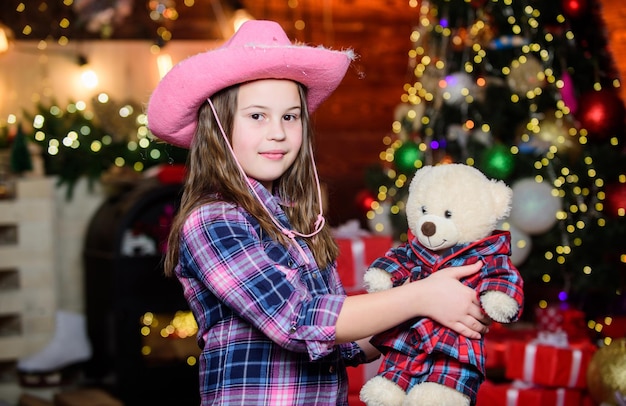 Memórias de infância Menina satisfeita presente de natal Presente de natal com o qual ela sonhou O melhor presente de todos Feliz ano novo conceito Sonhos se tornam realidade Garoto perto da árvore de natal segure ursinho de pelúcia brinquedo macio