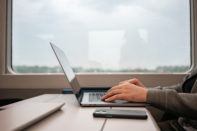 Men39s Hände tippen auf der Tastatur eines Silya-Laptops in einem Zug Europäische Züge reisen Smartphone Digitale Arbeit digitaler Nomade