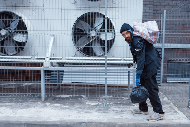 Foto mendigo com bolsa na rua da cidade.