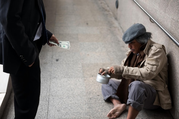 Foto mendigo sentado en la calle de la ciudad