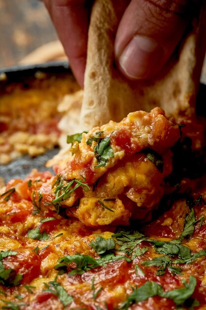 Menemen mit Eiern, Tomaten, Paprika und Gewürzen, serviert mit Brot in der Pfanne Türkisches Frühstück