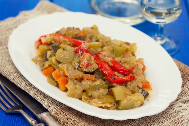 Menestra de verduras en plato blanco sobre superficie de madera