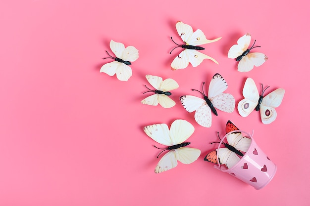 Menge der Kohlschmetterlinge fliegen heraus vom Eimer mit Herzen auf rosa Hintergrund