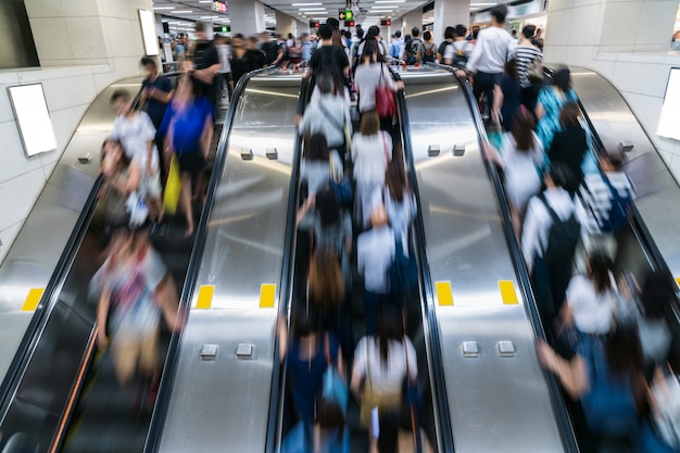 Menge von den Fußgängern unerkennbar, die in Rolltreppe am Hauptverkehrszeitmorgen vor Arbeitszeit in der U-Bahn-Transportnabe, Hong Kong, zentraler Bezirk gehen