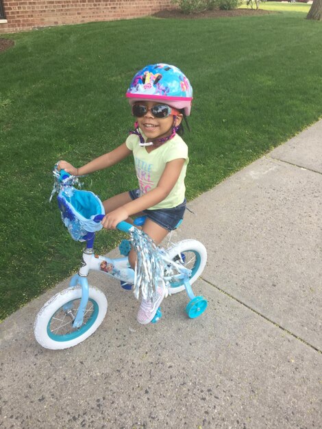 Foto menina a andar de bicicleta na relva