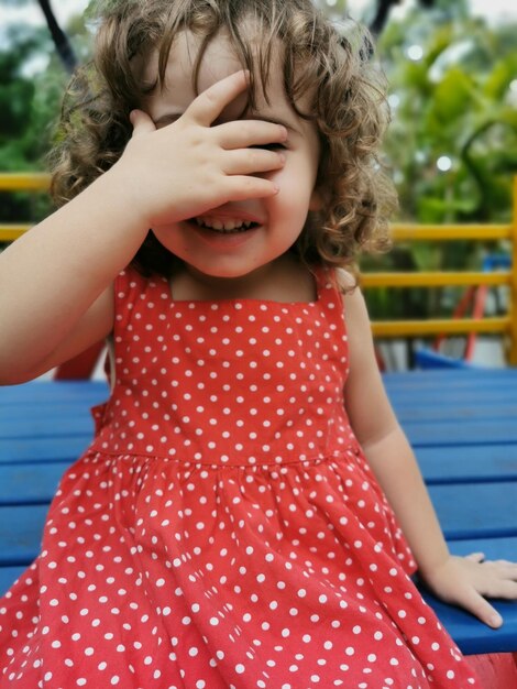 Foto menina a brincar a cobrir o rosto com a mão