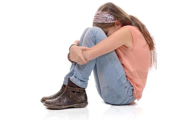 Foto menina abraçando joelhos contra fundo branco