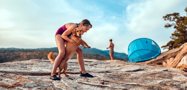 Menina abraçando seu cachorro na praia rochosa