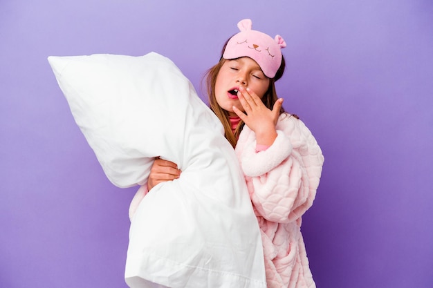 Menina abraçando um travesseiro feliz isolada em roxo