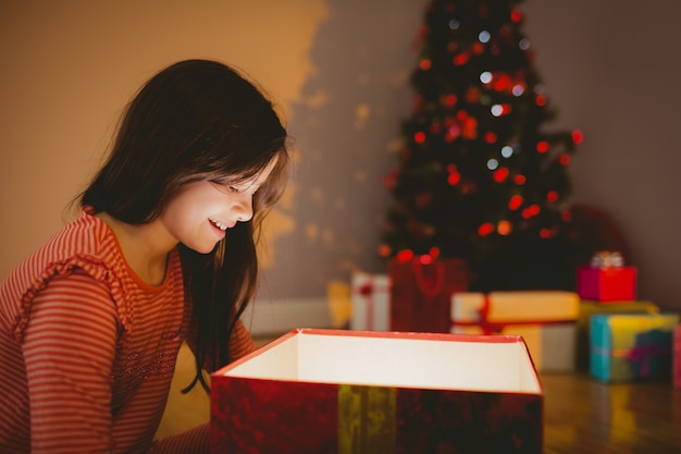 Menina abrindo um presente de Natal brilhante