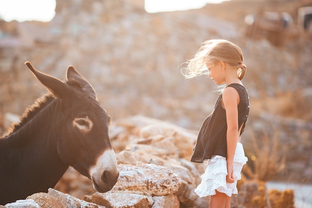 Menina acariciando um burro na ilha grega