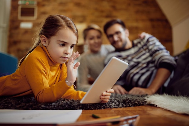 Menina acenando durante a chamada de vídeo sobre tablet digital em casa