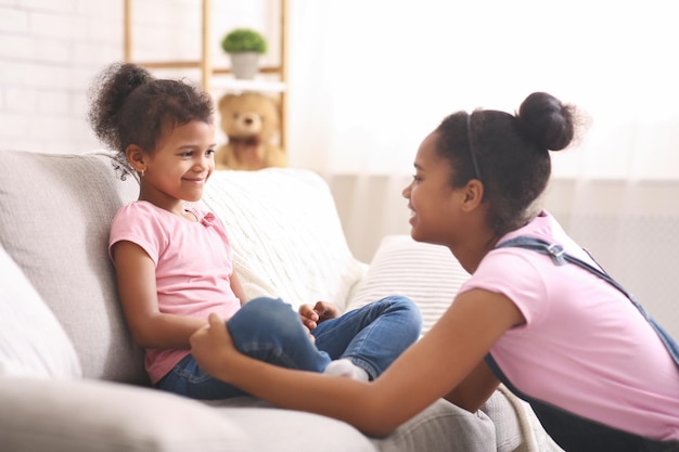 Menina adolescente africana conversando com sua irmãzinha em casa