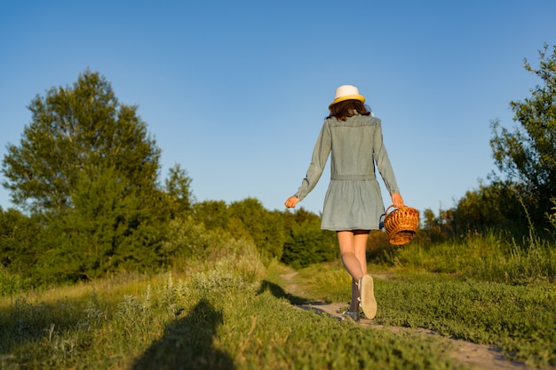 Menina adolescente ao ar livre com cesta de morangos, chapéu de palha