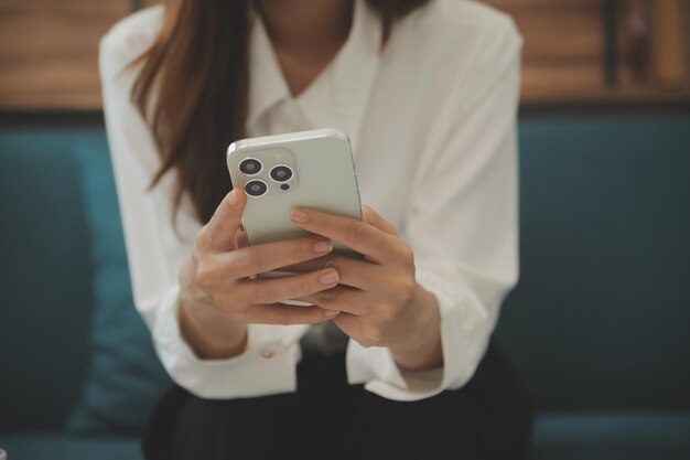 Menina adolescente asiática feliz segurando o dispositivo de computador pad usando tecnologia de tablet digital sentada no sofá em casa Jovem sorridente usando aplicativos de compras on-line lendo notícias navegando na internet no sofá