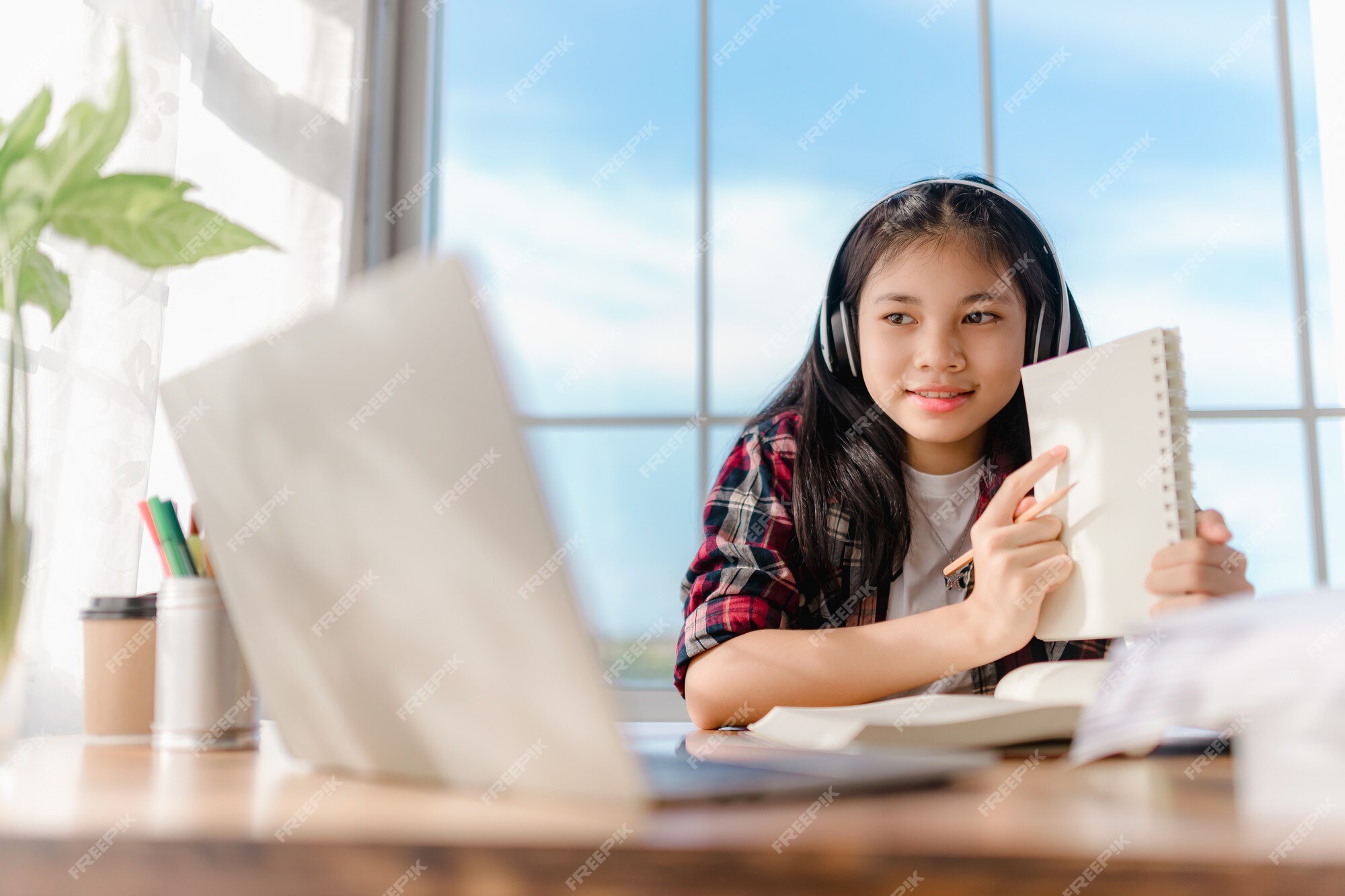 Linda garota asiática usando fone de ouvido aprendendo música de