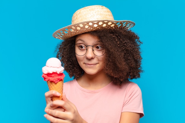 Menina adolescente bonita afro com chapéu e tomando um sorvete. conceito de verão