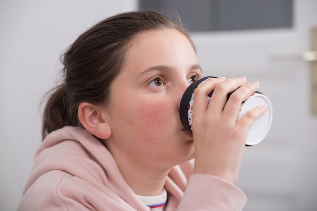 Menina adolescente bonita jovem com uma xícara de café de papel