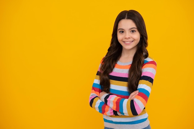 Menina adolescente bonitinha cruzando os braços sobre fundo amarelo Copie o espaço Emoções positivas e sorridentes de adolescente feliz de adolescente