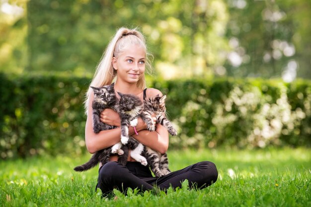 Menina adolescente brincando com gatinhos pequenos no dia de verão quente e ensolarado