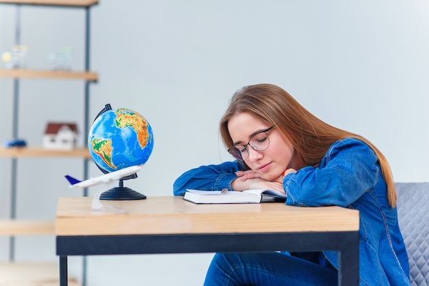 Menina adolescente cansada adormecer exausta após longas horas de aprender os preparativos para o exame. aluna de faculdade dorme à mesa.