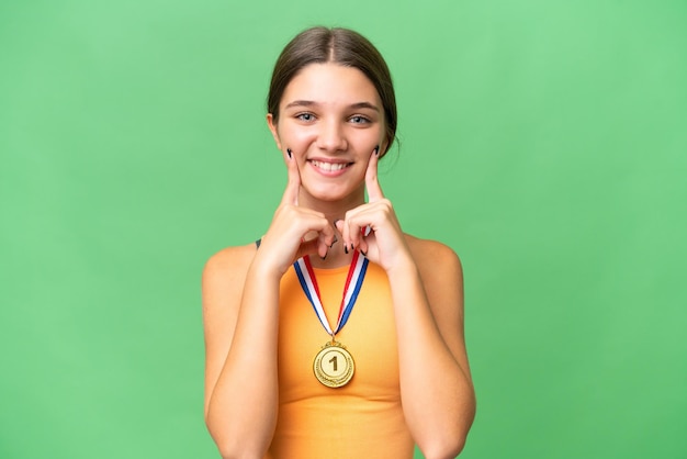 Menina adolescente caucasiana com medalhas sobre fundo isolado, sorrindo com uma expressão feliz e agradável