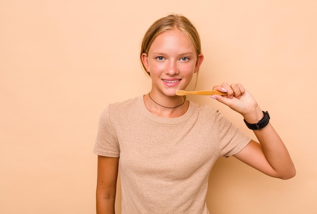 Menina adolescente caucasiana escovando os dentes isolados no fundo bege