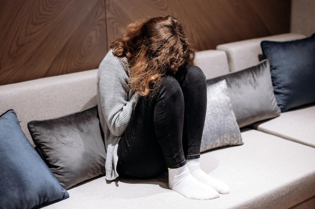 Menina adolescente chorando no sofá. Puberdade e depressão