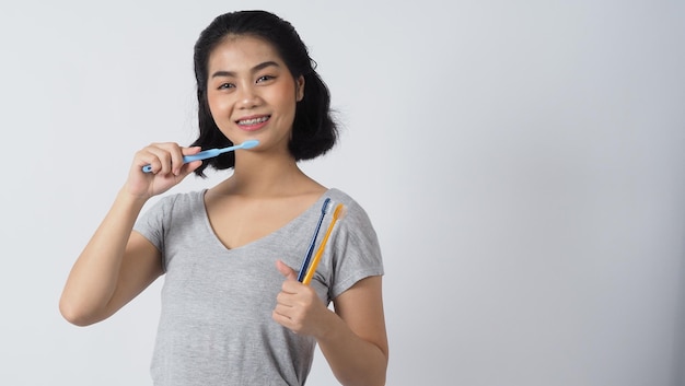 Menina adolescente com aparelho dental sorrindo segurando a escova de dentes e olhando para a câmera