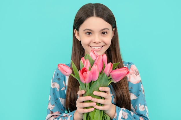 Menina adolescente com buquê de primavera em fundo azul floral presente rosto de criança feliz com tulipas