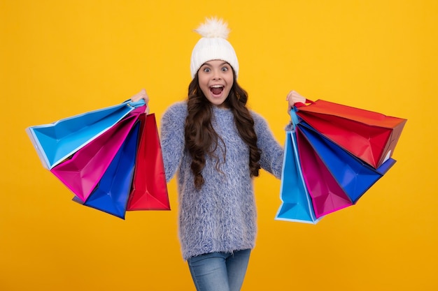 Menina adolescente com chapéu quente de inverno segura sacola de compras aproveitando a venda de inverno Venda de compras de outono