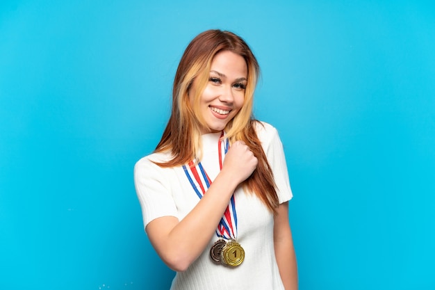 Menina adolescente com medalhas sobre fundo isolado comemorando vitória