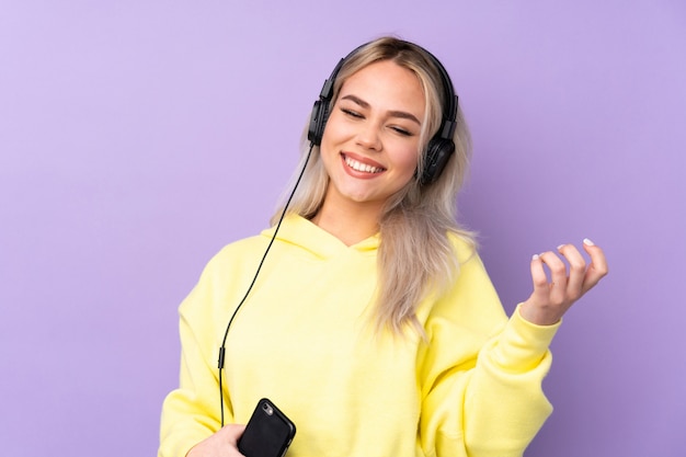 Menina adolescente com música roxa e fazendo gesto de guitarra