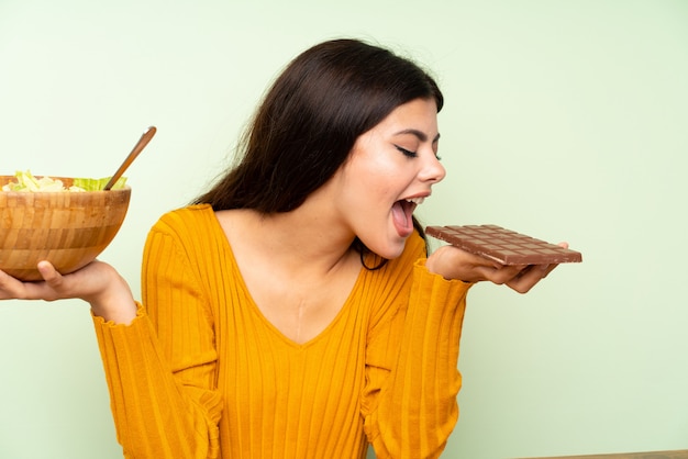 Menina adolescente com salada e chocolate