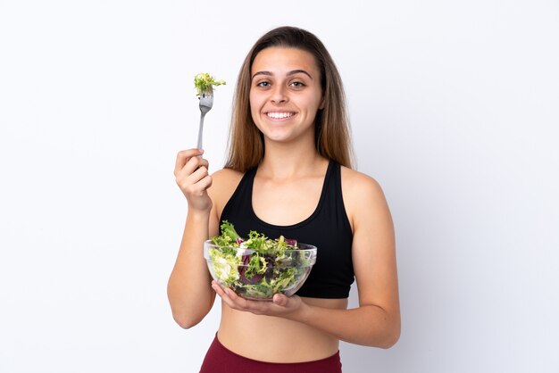 Menina adolescente com salada sobre parede isolada