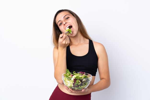 Menina adolescente com salada sobre parede isolada