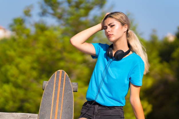 Menina adolescente com skate ao ar livre, tendo dúvidas