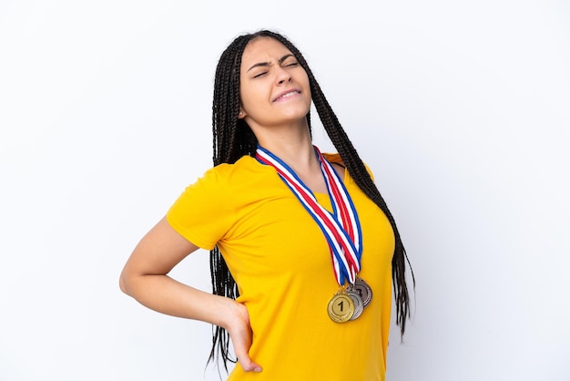 Menina adolescente com tranças e medalhas sobre fundo rosa isolado, sofrendo de dor nas costas por ter feito um esforço