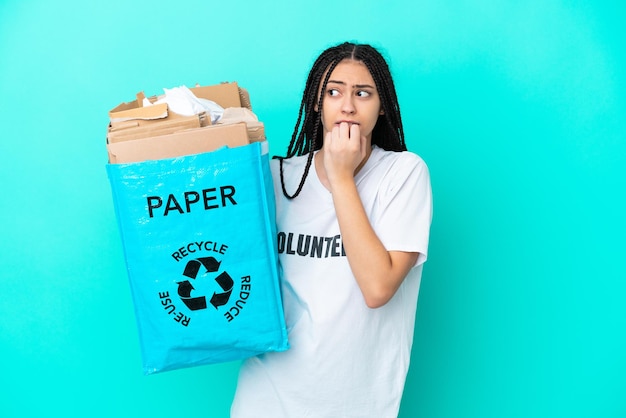 Menina adolescente com tranças segurando um saco para reciclar nervoso e assustado