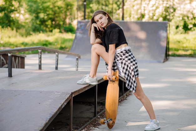 Menina adolescente com um skate andando na rampa no parque de skatistas