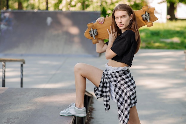 Menina adolescente com um skate andando na rampa no parque de skatistas