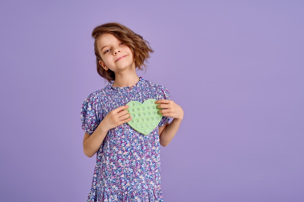 Menina adolescente com vestido estampado de flor azul de verão segurando um brinquedo anti-stress em lavanda