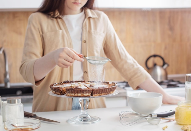 Foto menina adolescente cozinhando torta de nozes na cozinha
