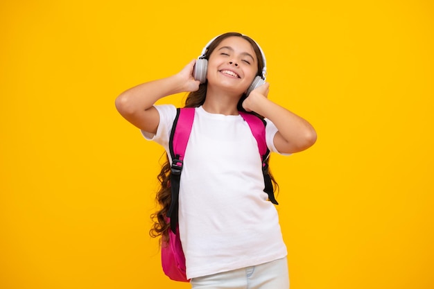 Menina adolescente da escola em fones de ouvido com mochila escolar fundo isolado de estudante adolescente aprendendo música