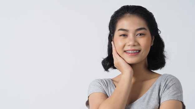 Menina adolescente de aparelho dentário sorrindo, olhando para a frente. dentes brancos com aparelho azul. cuidado dental. sorriso de mulher asiática com acessórios ortodônticos. aparelho oral.