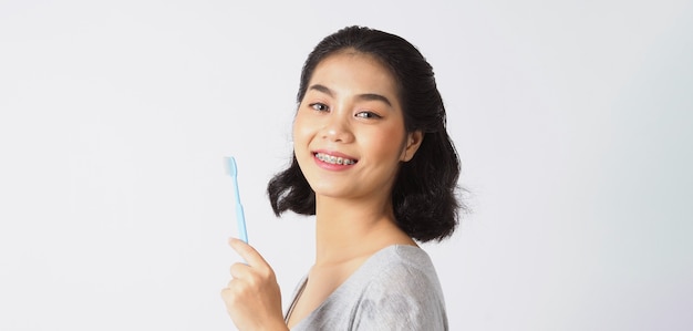 Menina adolescente de aparelho dentário sorrindo, olhando para uma câmera. dentes brancos com aparelho azul. cuidado dental. sorriso de mulher asiática com acessórios ortodônticos. odontologia estética, tratamento ortodôntico. tiro do estúdio.