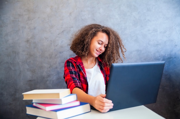Menina adolescente de cabelos cacheados trabalhando no laptop